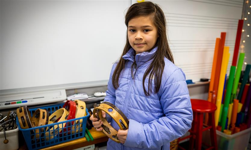 A girl smiles while holding an instrument